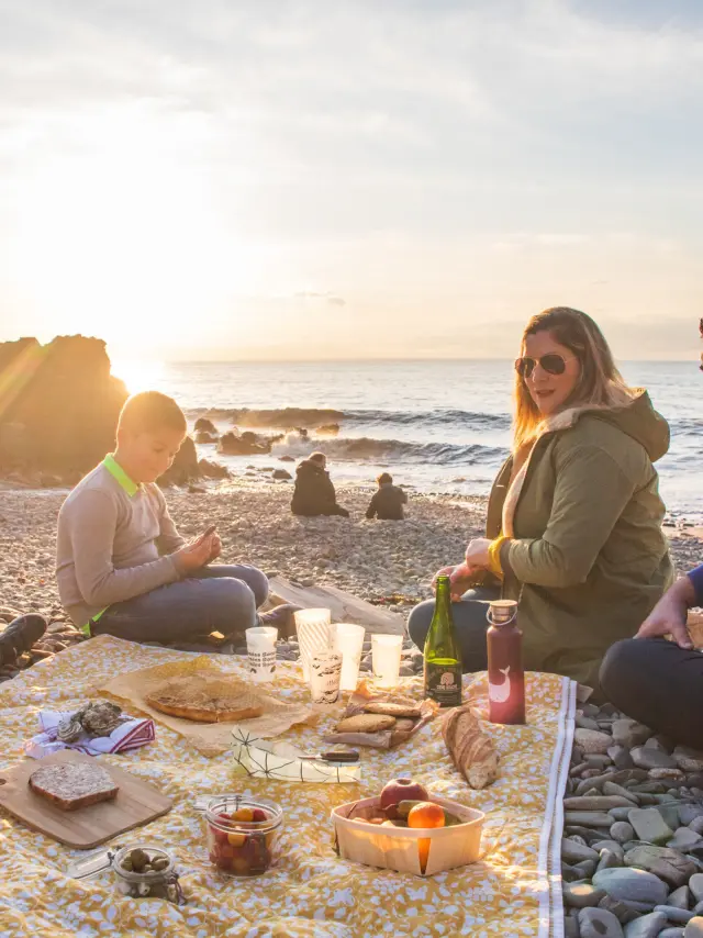 A family picnic on the pebbles of Le Lude harbour at sunset