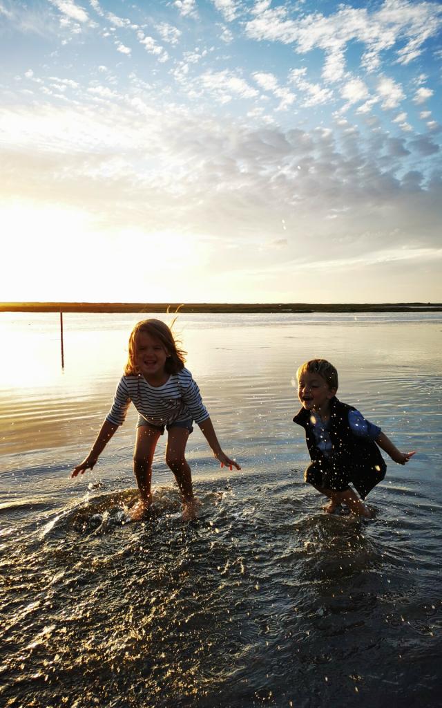 Des enfants jouent les pieds dans l'eau sur la route submersible de Bricqueville-sur-Mer dans le havre de la Vanlée lors d'une grande marée
