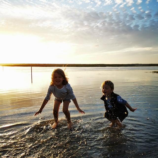 Des enfants jouent les pieds dans l'eau sur la route submersible de Bricqueville-sur-Mer dans le havre de la Vanlée lors d'une grande marée